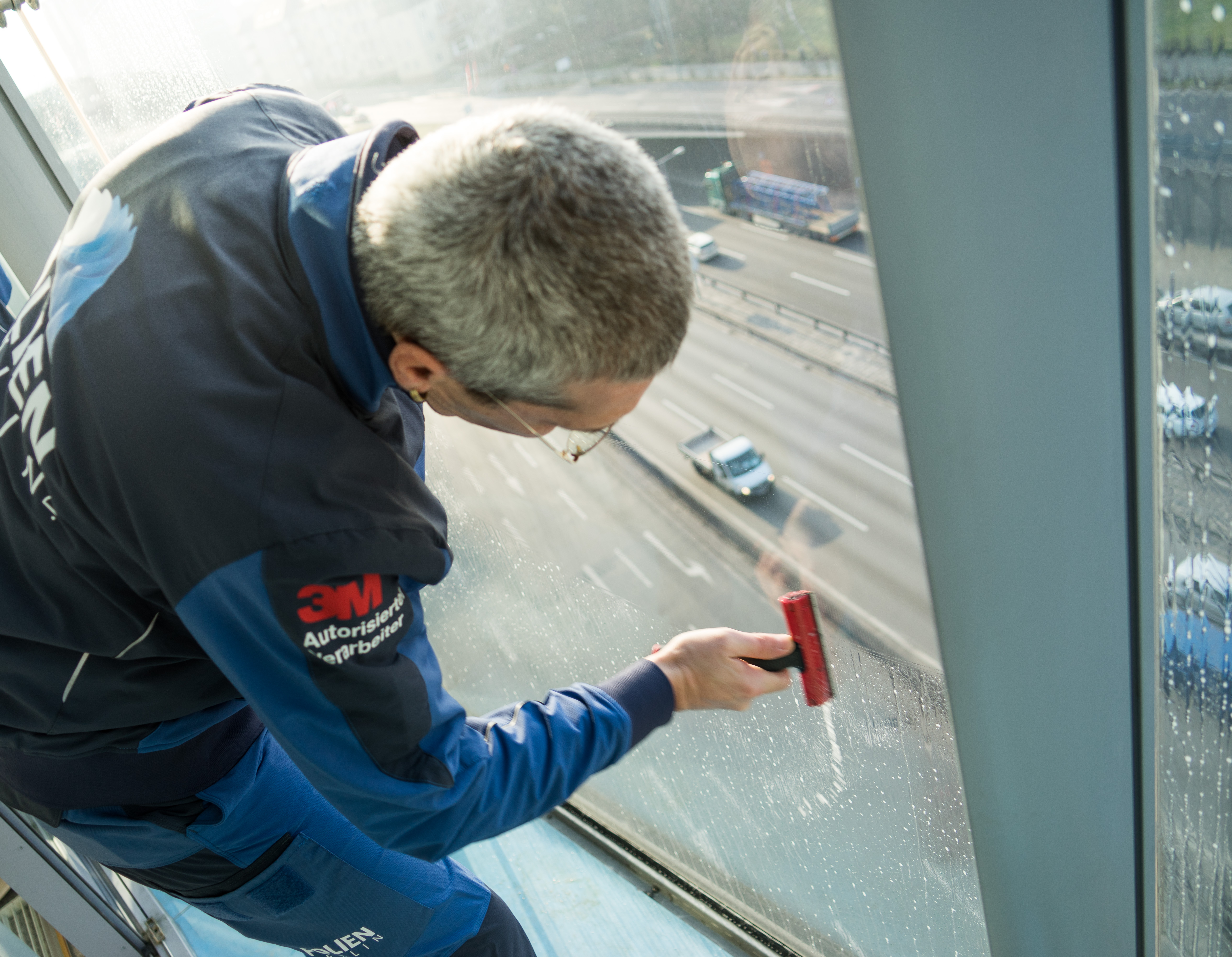 Ein Mitarbeiter säubert das Fenster im Inneren einen hohen Gebäudes.